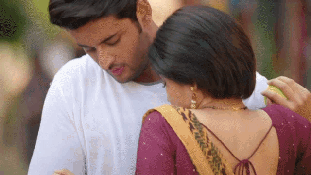 a man and a woman are hugging and the woman is wearing a purple blouse