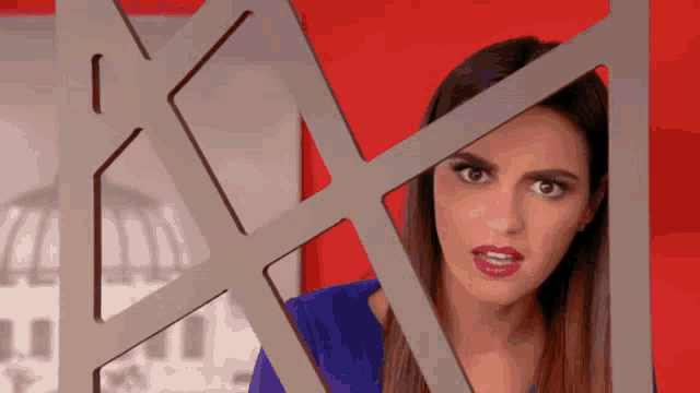 a woman in a blue dress is looking through a fence