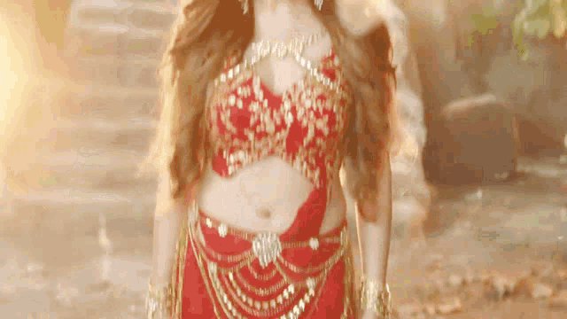 a woman in a red and gold costume is standing in front of a fire