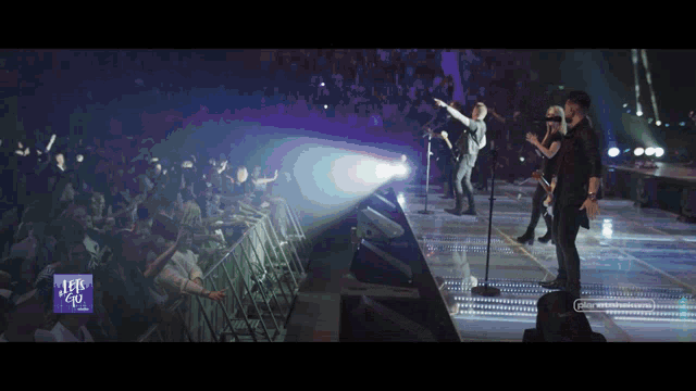 a group of people standing on a stage in front of a sign that says let 's go music