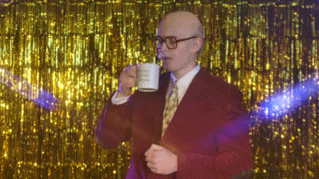 a man in a suit and tie is drinking from a mug that says ' i 'm sorry ' on it .