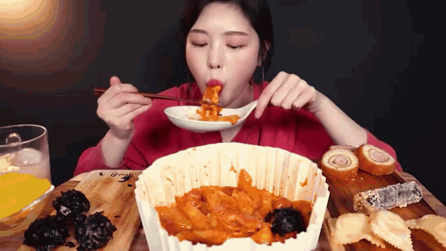 a woman is eating a bowl of food with chopsticks while sitting at a table