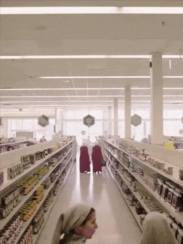 a woman in a head scarf is walking down a store aisle