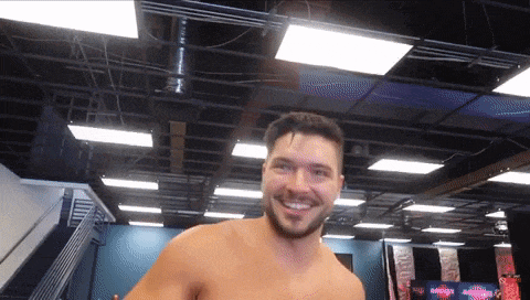 a man without a shirt is smiling in a gym with a sign that says ' a ' on it