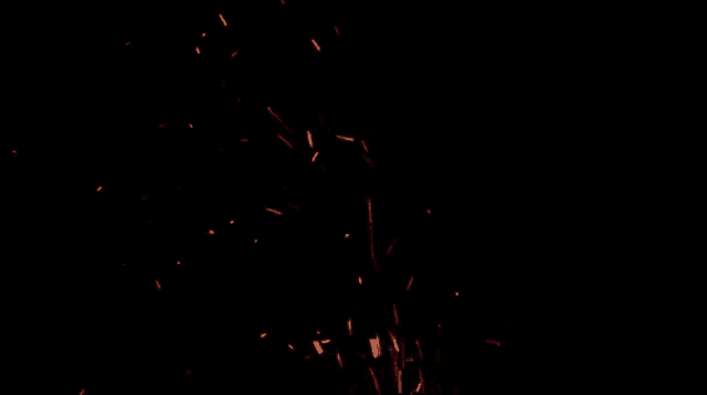 a bunch of sparks are flying in the dark on a black background