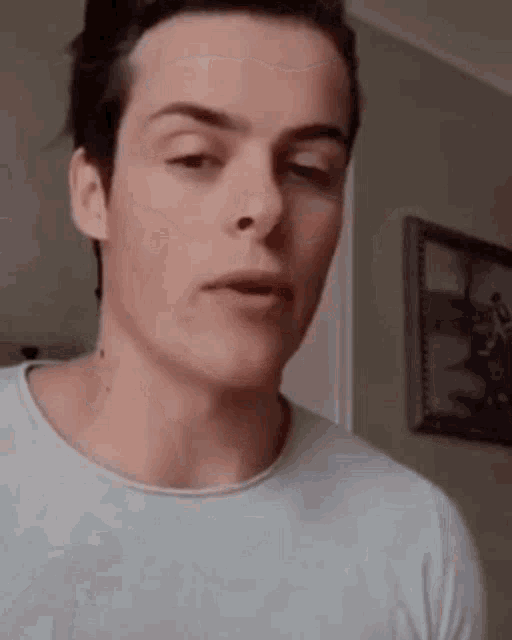 a young man in a white shirt is making a funny face in a living room .
