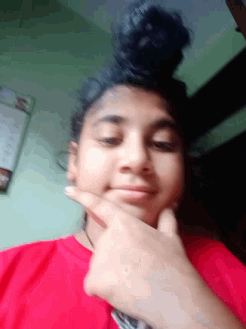 a girl in a red shirt is making a funny face with her finger on her chin