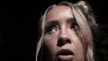 a close up of a woman 's face in the dark with her mouth open .
