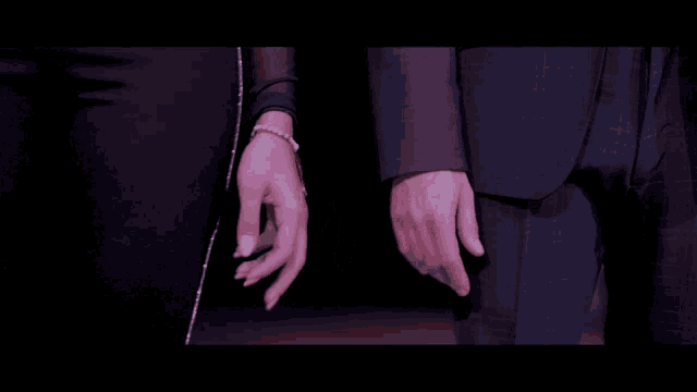 a man and a woman are holding hands in a dark room