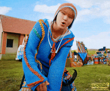a person wearing a blue sweater and a beanie stands in a field