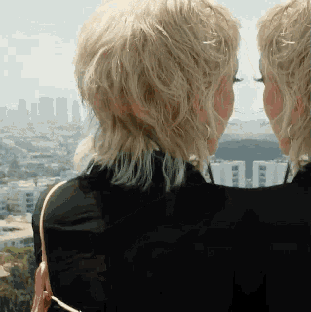 two blonde women are looking at a city skyline