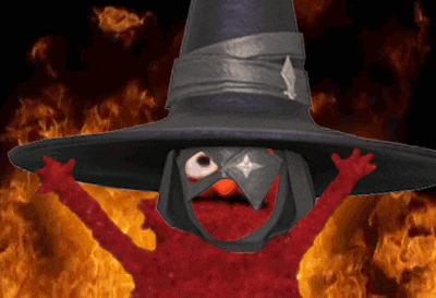 elmo is wearing a witch hat and a mask while standing in front of flames
