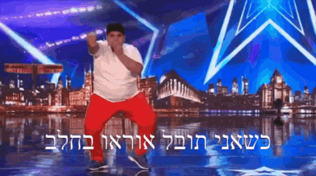 a man in a white shirt and red pants is dancing on a stage in front of a blue background