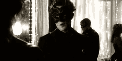 a man wearing a mask is standing in front of a mirror in a black and white photo .