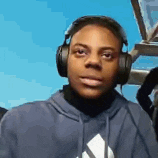 a young man wearing headphones and a blue hoodie is sitting in a plane .
