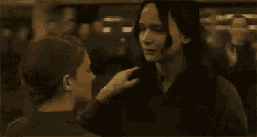 a man is touching a woman 's hair in a crowded room .