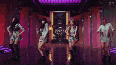 a group of young women are dancing together on a stage in a room .