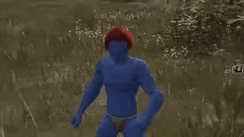 a blue man with a red hat on stands in the grass