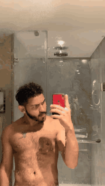 a shirtless man is taking a selfie in a bathroom mirror