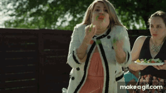 a woman blowing bubbles while another woman holds a plate of food in front of her