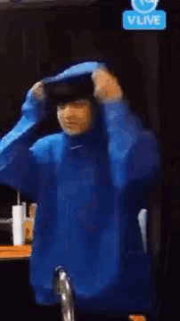a person in a blue hoodie is standing in front of a v live sign .