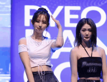 two women are standing in front of a sign that says pyeo on it