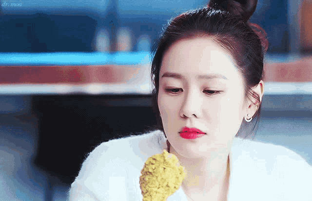 a woman with red lips is eating a piece of food