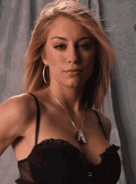 a woman wearing a black bra and hoop earrings has a necklace around her neck that says ' i love you '