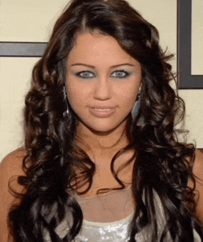 a woman with long curly hair and blue eyes is wearing earrings