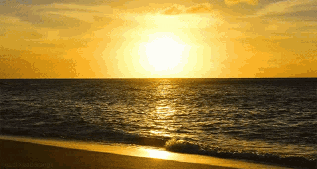 the sun is setting over a body of water and a beach is visible