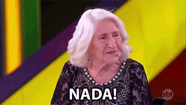a woman with white hair is sitting in front of a colorful background and says nada .