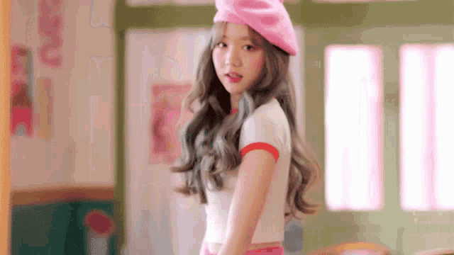 a young woman wearing a pink beret and a white shirt is standing in a room .