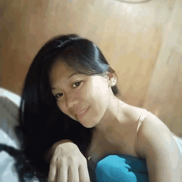 a woman with long black hair is smiling and laying on a bed