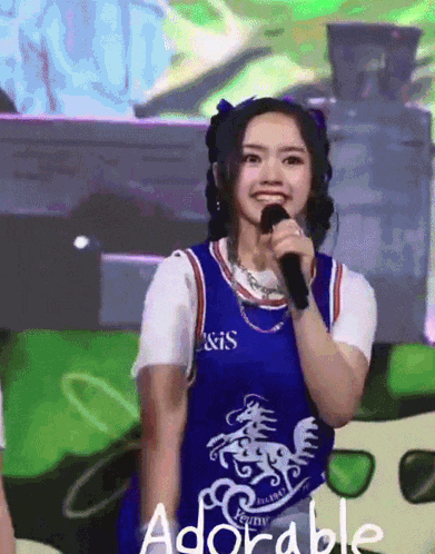 a girl holding a microphone with the word adorable on the bottom right