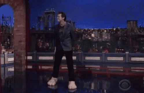 a man in a suit is dancing on a stage with giant feet .