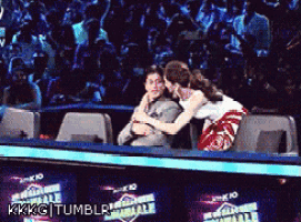 a man and a woman are hugging in front of a crowd and the words kkkg tumblr are on the bottom right