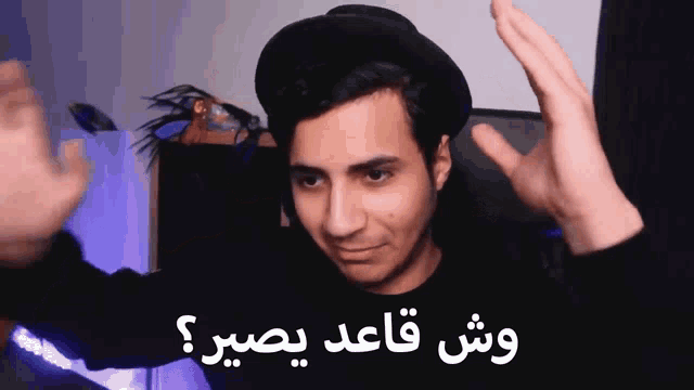 a man wearing a black hat and a black shirt is making a funny face