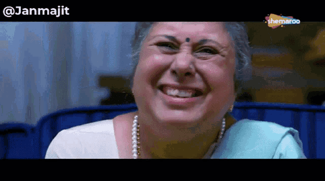 a woman is smiling in front of a screen that says ' shemaroo ' on it