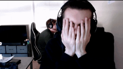 a man covering his face with his hands while wearing headphones