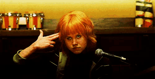a girl with red hair is making a gun gesture