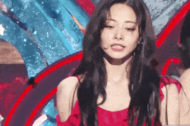 a woman in a red dress is standing on a stage and looking at the camera