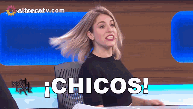 a woman sitting at a table with the words chicos written on it
