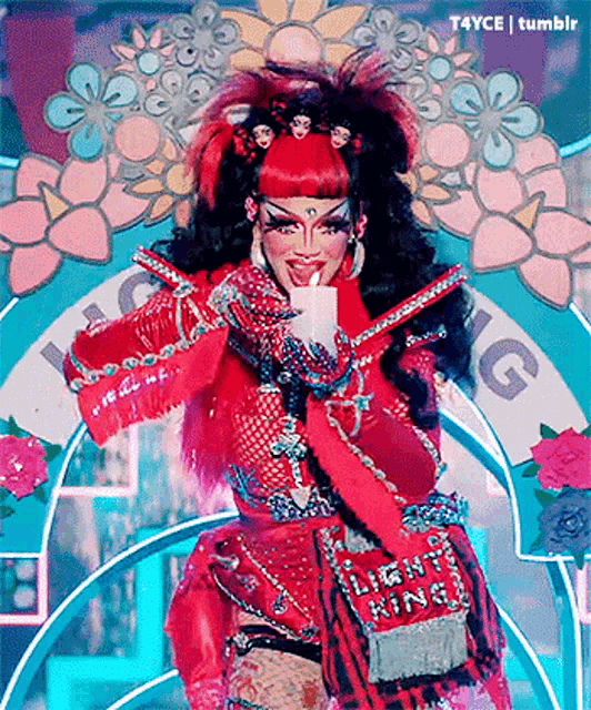 a drag queen is holding a candle in her hand .
