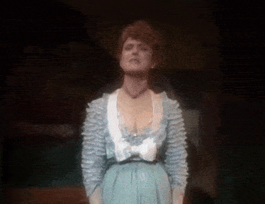 a woman in a blue dress is standing on a stage and singing .