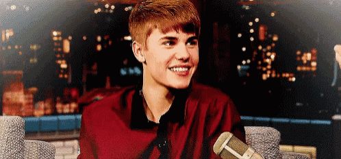 a young man in a red shirt is sitting in front of a microphone