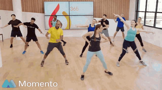 a group of people are dancing in front of a monitor that says 365