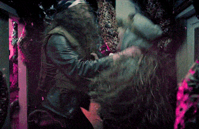 a man in a leather jacket is holding a woman 's hand