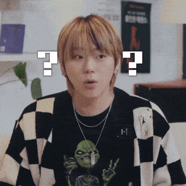 a young man wearing a black and white checkered sweater has a question mark above his head