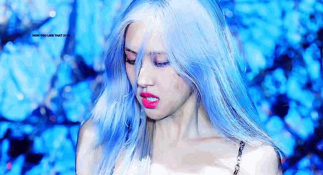 a close up of a woman with blue hair and red lips .