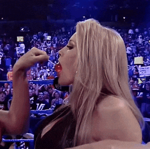 a woman in a wrestling ring drinking from a bottle with the letter t on it